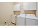 Bright laundry room with white cabinets and a washing machine and dryer at 16955 W Cypress St, Goodyear, AZ 85395