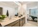 Bright bathroom featuring double sinks, quartz counters, and a modern design, adjoining the main bedroom suite at 17341 W Fallen Leaf Ln, Surprise, AZ 85387
