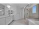 Modern bathroom features dual sinks, a glass enclosed shower, and a soaking tub at 17827 W Medlock Dr, Litchfield Park, AZ 85340