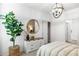 Cozy bedroom with a dresser, round mirror, modern lighting and leafy plant at 18353 W Gray Fox Trl, Wittmann, AZ 85361