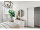 Well-lit bedroom featuring a dresser with decor, leafy plant, and round mirror at 18353 W Gray Fox Trl, Wittmann, AZ 85361