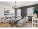 Open-concept living room featuring a comfortable sofa, stylish decor, and ample natural light from large windows at 18353 W Gray Fox Trl, Wittmann, AZ 85361