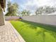 A well-maintained backyard featuring artificial grass, privacy wall, and playful slide set under a sunny sky at 1892 S Arroyo Ln, Gilbert, AZ 85295