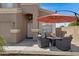 Relaxing outdoor patio area features a table with four chairs, a fire pit and a large parasol umbrella at 19616 N Toya St, Maricopa, AZ 85138