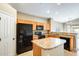 Functional kitchen with wooden cabinets, tile flooring, black appliances, and an island at 1979 N Vista Ln, Casa Grande, AZ 85122