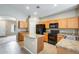 Well-lit kitchen features tile floors, wooden cabinets, an island, and black appliances at 1979 N Vista Ln, Casa Grande, AZ 85122