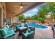 Inviting backyard featuring a covered patio, comfortable seating, and a sparkling pool with waterfall feature at 2452 W Enfield Way, Chandler, AZ 85286