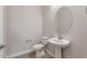 Bright half bathroom featuring a round mirror and pedestal sink at 26696 W Siesta Ln, Buckeye, AZ 85396