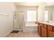 Bright bathroom featuring tile floors, shower, soaking tub, and vanity with wood cabinets and solid surface counters at 3107 S 74Th Ln, Phoenix, AZ 85043
