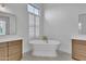 Bright bathroom showcasing a soaking tub centered between matching vanities and natural light from shuttered windows at 3461 E Indigo Cir, Mesa, AZ 85213