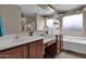 Bathroom with a double sink vanity, and a white bathtub with a window above it at 4364 S Tatum Ln, Gilbert, AZ 85297