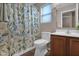 Neutral bathroom with wooden cabinets, white sink, leafy shower curtain, and window with blinds at 4364 S Tatum Ln, Gilbert, AZ 85297