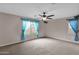 Spacious main bedroom with plush carpet, ceiling fan, and two windows dressed with sheer blue curtains at 4364 S Tatum Ln, Gilbert, AZ 85297