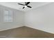 Bright, empty bedroom with wood look tile flooring, ceiling fan, and plantation shutters at 4417 N 156Th Dr, Goodyear, AZ 85395