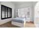 Cozy bedroom with a Murphy bed, hardwood floors, shuttered window, and bathroom access at 4901 E Lafayette Blvd, Phoenix, AZ 85018