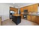 Well-equipped kitchen featuring stainless steel appliances, tile flooring, an island, and classic wood cabinetry at 5959 W Lone Cactus Dr, Glendale, AZ 85308