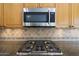 Close-up of a stainless-steel cooktop and microwave, complemented by granite countertops and a decorative backsplash at 5959 W Lone Cactus Dr, Glendale, AZ 85308