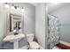 This bathroom features a pedestal sink with a wood-trimmed mirror and a colorful patterned shower curtain at 630 S Boulder Ct, Gilbert, AZ 85296