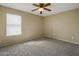 Neutral bedroom showcasing natural light through a window and plush carpeting, with a ceiling fan at 7009 W Taro Ln, Glendale, AZ 85308