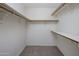 Spacious walk-in closet featuring built-in shelving, providing ample storage with neutral carpet at 7009 W Taro Ln, Glendale, AZ 85308