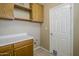 Functional laundry room featuring built-in cabinets, a countertop, and a white paneled door at 7009 W Taro Ln, Glendale, AZ 85308