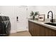 Laundry room area with front load washer, wood cabinets with gray countertop, and black modern faucet at 7670 E Sierra Vista Dr, Scottsdale, AZ 85250