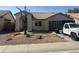 Beige single-story home featuring a red rock yard and a red tile roof and a trash truck parked on the right side at 8349 W Holly St, Phoenix, AZ 85037