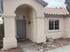Inviting front entryway with an arched portico, stone accents, and a gray front door featuring sidelight windows at 8349 W Holly St, Phoenix, AZ 85037