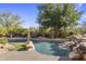 Tranquil backyard pool with rock waterfall feature, surrounded by lush greenery and mature trees at 10040 E Happy Valley Rd # 479, Scottsdale, AZ 85255