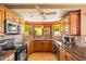 Sunlit kitchen featuring black appliances, wooden cabinetry, granite countertops, and tile backsplash at 10837 W Cottonwood Ln, Avondale, AZ 85392
