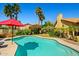 Beautiful backyard pool surrounded by lush landscaping with a red umbrella for shade at 10837 W Cottonwood Ln, Avondale, AZ 85392
