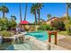 Inviting backyard pool with a spa, red umbrella, lounge chairs and lush tropical landscaping at 10837 W Cottonwood Ln, Avondale, AZ 85392