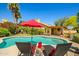 Tranquil backyard pool setting with lounge chairs, mature landscaping, and a red umbrella at 10837 W Cottonwood Ln, Avondale, AZ 85392