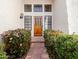 A charming home entryway with a wooden door, black framed windows, and vibrant green landscaping at 1110 N Gull Haven Ct, Gilbert, AZ 85234