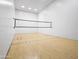 Indoor racquetball court featuring smooth wooden flooring, solid white walls, and a regulation net for competitive play at 1110 N Gull Haven Ct, Gilbert, AZ 85234