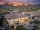 Aerial view of a property showcasing the outdoor patio with seating, hot tub, mountain views, and desert landscaping at 11339 E Beck Ln, Scottsdale, AZ 85255