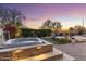 Outdoor jacuzzi with nearby seating, surrounded by trees, shrubs and desert landscaping with beautiful sunset views at 11339 E Beck Ln, Scottsdale, AZ 85255