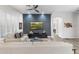 Living room showcasing dark accent wall, flatscreen TV, hardwood-style floors, and access to the hallway at 11339 E Beck Ln, Scottsdale, AZ 85255