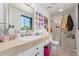 Bathroom with tiled countertop vanity, glass shower, a large mirror, and a bright window at 11827 S Montezuma Ct, Phoenix, AZ 85044