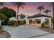 Luxurious home with porte cochere and expansive driveway surrounded by lush tropical landscaping and warm lighting at 11827 S Montezuma Ct, Phoenix, AZ 85044