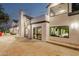 Rear exterior view of a modern home with a stone patio and well-lit windows reflecting the interior at 11827 S Montezuma Ct, Phoenix, AZ 85044