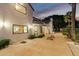 Exterior of a modern home with stone patio, showing windows to kitchen and dining area; tall palm trees at 11827 S Montezuma Ct, Phoenix, AZ 85044