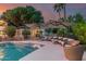Relaxing patio area with ample seating, umbrellas for shade, and views of the sparkling pool and lush garden at 11827 S Montezuma Ct, Phoenix, AZ 85044