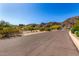 Paved neighborhood street with desert vegetation, homes, and a mountain backdrop under a bright blue sky at 11827 S Montezuma Ct, Phoenix, AZ 85044