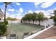 Backyard tennis court surrounded by mature trees, flowers and greenery under a bright blue sky at 11827 S Montezuma Ct, Phoenix, AZ 85044
