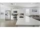 Bright kitchen with white cabinets, stainless steel appliances, a center island, and tile flooring flowing into the living area at 12472 W Kaler Dr, Glendale, AZ 85307
