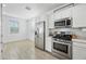 Well-lit kitchen featuring stainless steel appliances, white cabinetry, and wood-look tile flooring at 12472 W Kaler Dr, Glendale, AZ 85307
