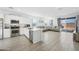 Open-concept living area featuring a modern kitchen, tile floors, and a comfortable gray sofa with backyard access at 12472 W Kaler Dr, Glendale, AZ 85307