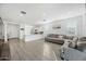 Open-concept living space featuring a gray sectional sofa, tile flooring, and an adjoining kitchen with white cabinets at 12472 W Kaler Dr, Glendale, AZ 85307