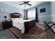 Light blue bedroom showcasing ceiling fan, large bed with wood frame, red accent rug, and mounted TV at 15515 N 174Th Ave, Surprise, AZ 85388